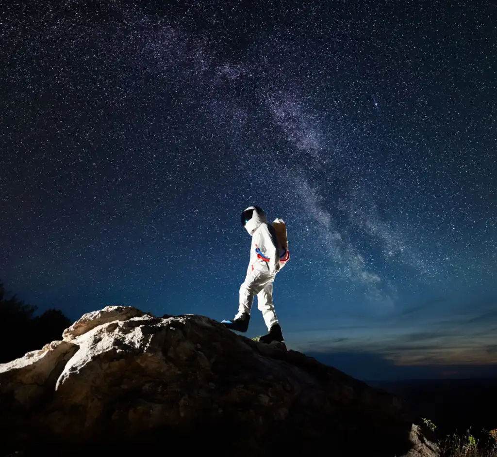 Astronauta che cammina su una collina rocciosa sotto il cielo stellato
